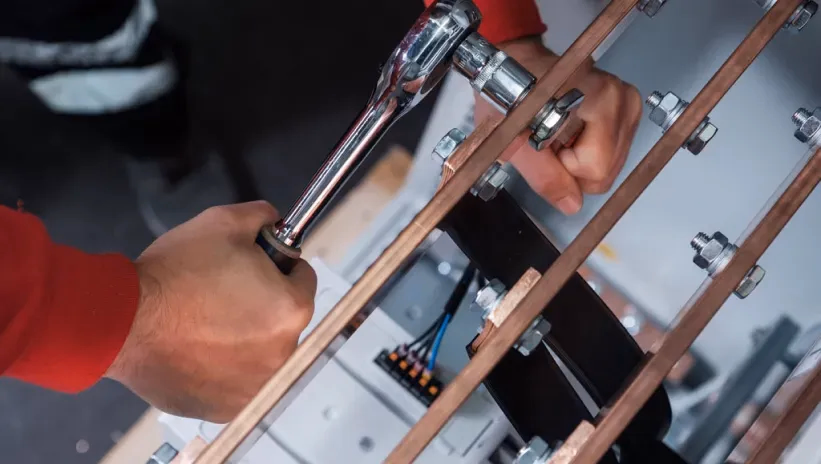 Técnico ajustando conexiones en el sistema eléctrico de un grupo electrógeno.