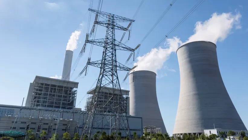 Planta de generación de energía con torres de enfriamiento y líneas de transmisión eléctrica.