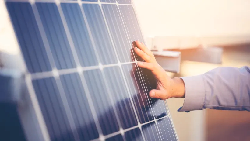 Mano revisando un panel solar en una instalación de sistemas híbridos solares.