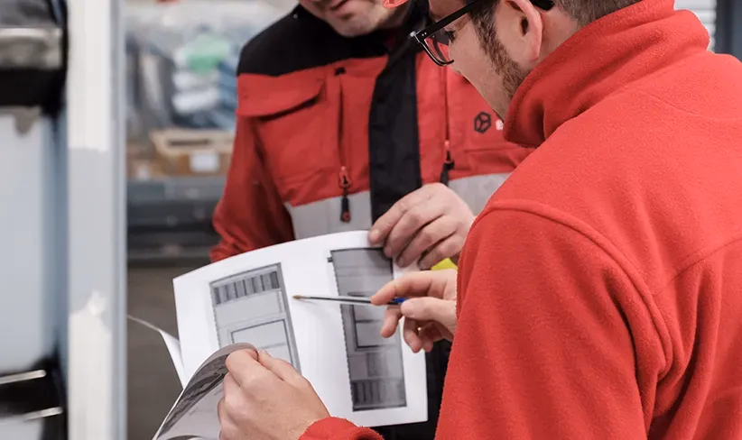 Técnicos analizando planos y detalles de un proyecto eléctrico en un entorno industrial